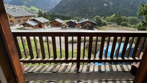 A wooden balcony overlooking a mountain village with traditional wooden buildings and a clear view of the surrounding landscape. - Individual cottage 10-12 person  (Châtel)