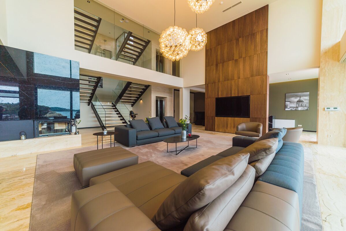 A spacious living area with a large sectional sofa, a coffee table, and a staircase leading to an upper level.