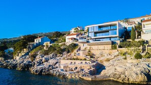 A coastal property with a stone staircase leading to a terrace, modern buildings with large windows, and a clear view of the sea. - PureLuxuryExclusiveVillaStateOfTheArtVillaExcellentLocationPrivateBeach (Zaton)