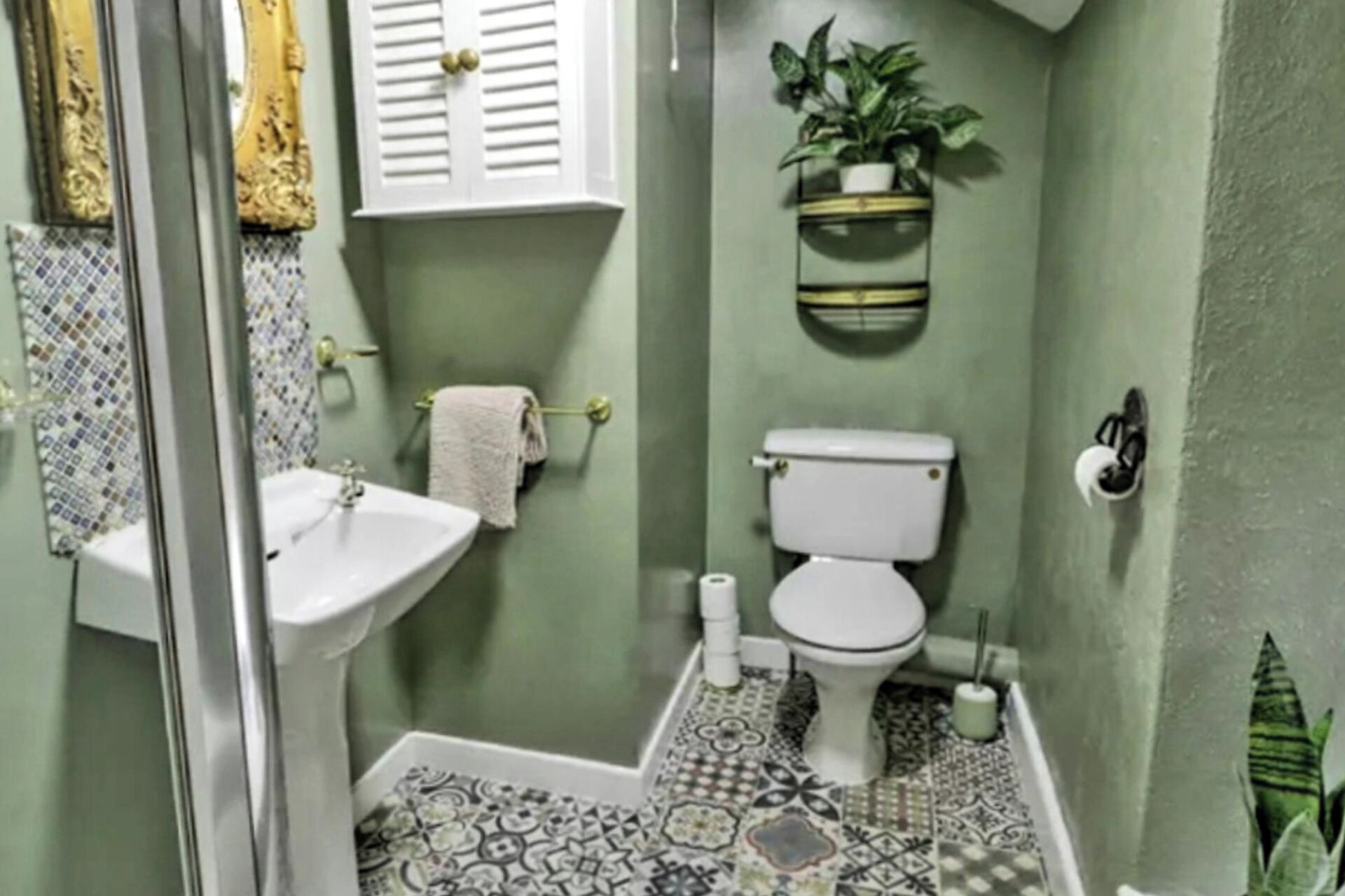 Une salle de bain avec un lavabo blanc, des toilettes et des carreaux de sol à motifs.