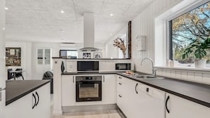 A modern kitchen with white cabinetry, a black countertop, and stainless steel appliances. - 3 bedroom amazing home in Storvorde (Storvorde)