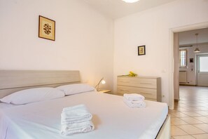 A hotel room with a bed, a nightstand, a dresser, and a framed picture on the wall.