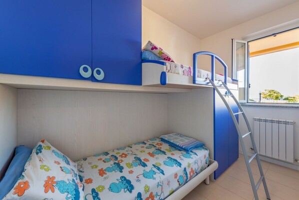 A bunk bed room with a ladder, a window with a view, and a radiator.