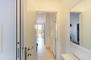 Un couloir avec une porte blanche, un radiateur et un miroir accroché au mur.