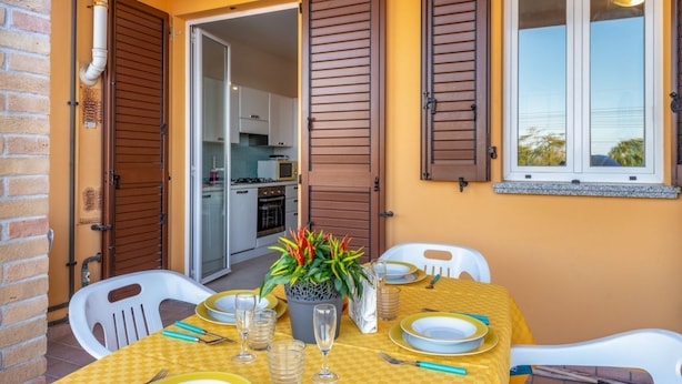 A dining area with a table set for four, a potted plant, and a view of the kitchen through an open door. - Bright and comfortable apartment, able to accommodate up to 4 people, with a large double bedroom and bedroom with a bunk bed, equipped terrace, living room and kitchenette. Ideal for a relaxing beach holiday, a few meters from the Blue Beach and in a co (Marotta)