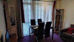 Un espace repas comprenant une table et des chaises, un canapé et un meuble.