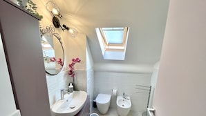 Ein Badezimmer mit Oberlicht, Waschbecken, Toilette und Bidet.
