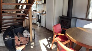 Una cocina con estufa, refrigerador y chimenea. Hay una mesa de comedor con sillas y una chimenea.