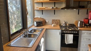 Una cocina compacta con estufa a gas, lavaplatos doble y encimeras de madera.