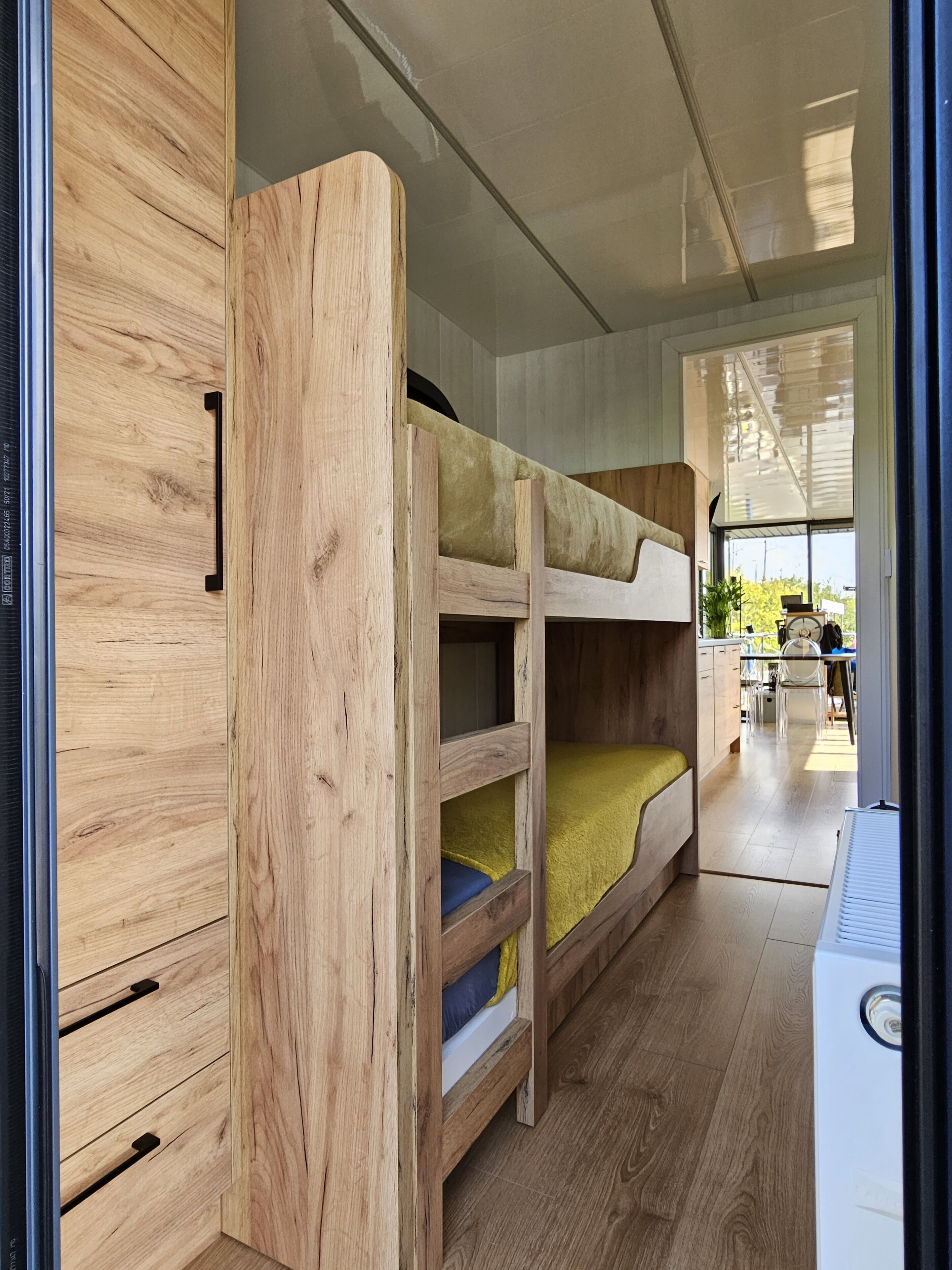 A compact, modern interior with a bunk bed and a kitchenette area.