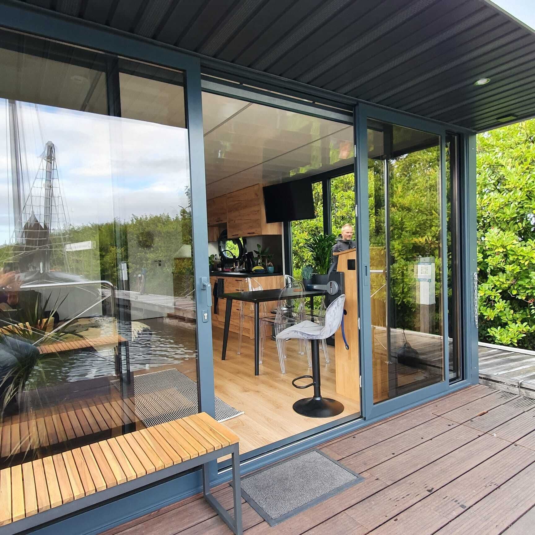 A modern outdoor kitchen area with a wooden deck, a dining table, and a chair.