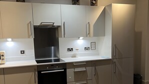 Eine moderne Küche mit weißen Schränken, Edelstahlgeräten und Holzboden.