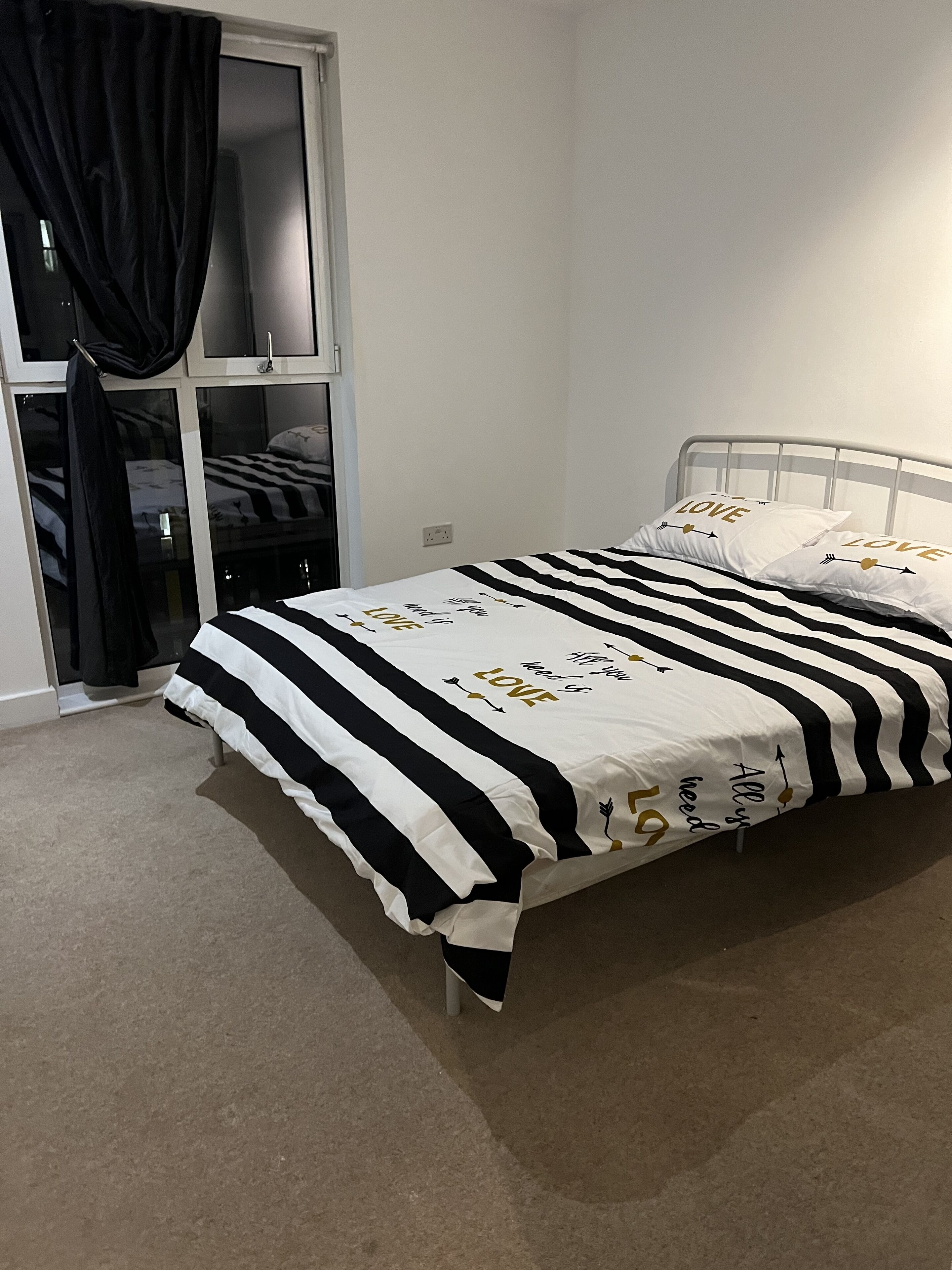 A bedroom with a bed, a window with curtains, and a closet.