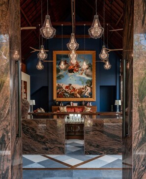 A lobby with a marble floor, a large painting, and multiple hanging chandeliers. - La Reserve 1785 Canggu - Adults Only (Canggu)