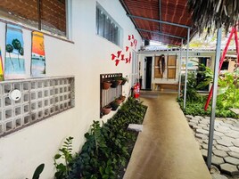 Un pasillo cubierto con plantas en macetas, un extintor y una ventana con vista al cielo.