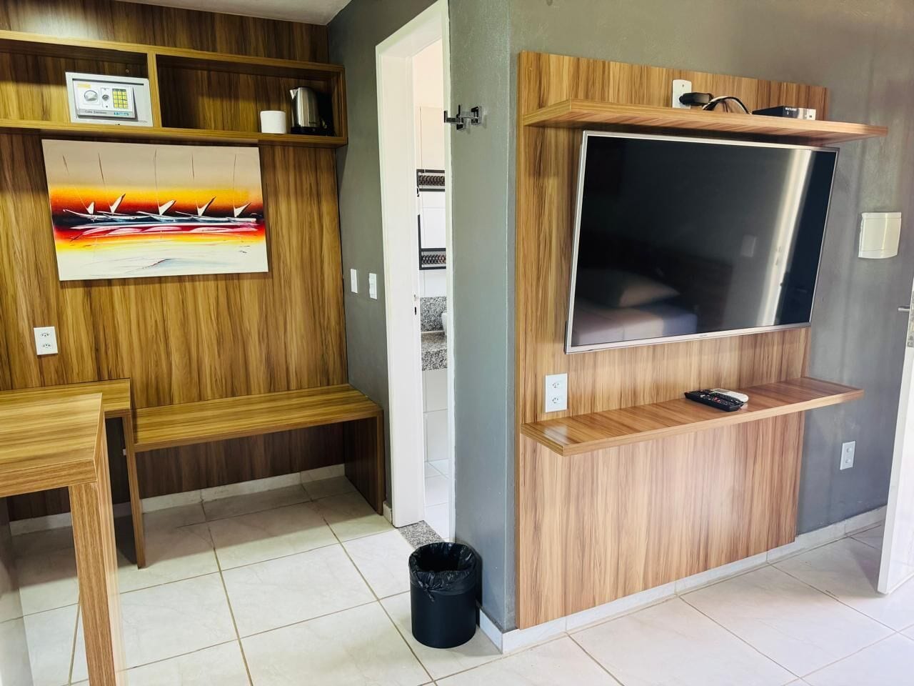 A modern kitchen with wooden cabinetry, a built-in TV, and a bench.