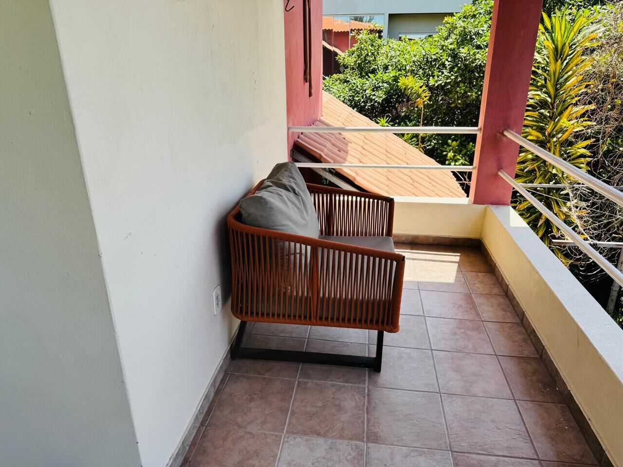 A balcony with a wooden bench and a tiled floor.