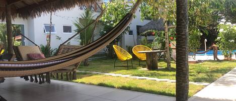 Relax in a serene outdoor oasis with a shaded hammock, pool, and lush greenery.