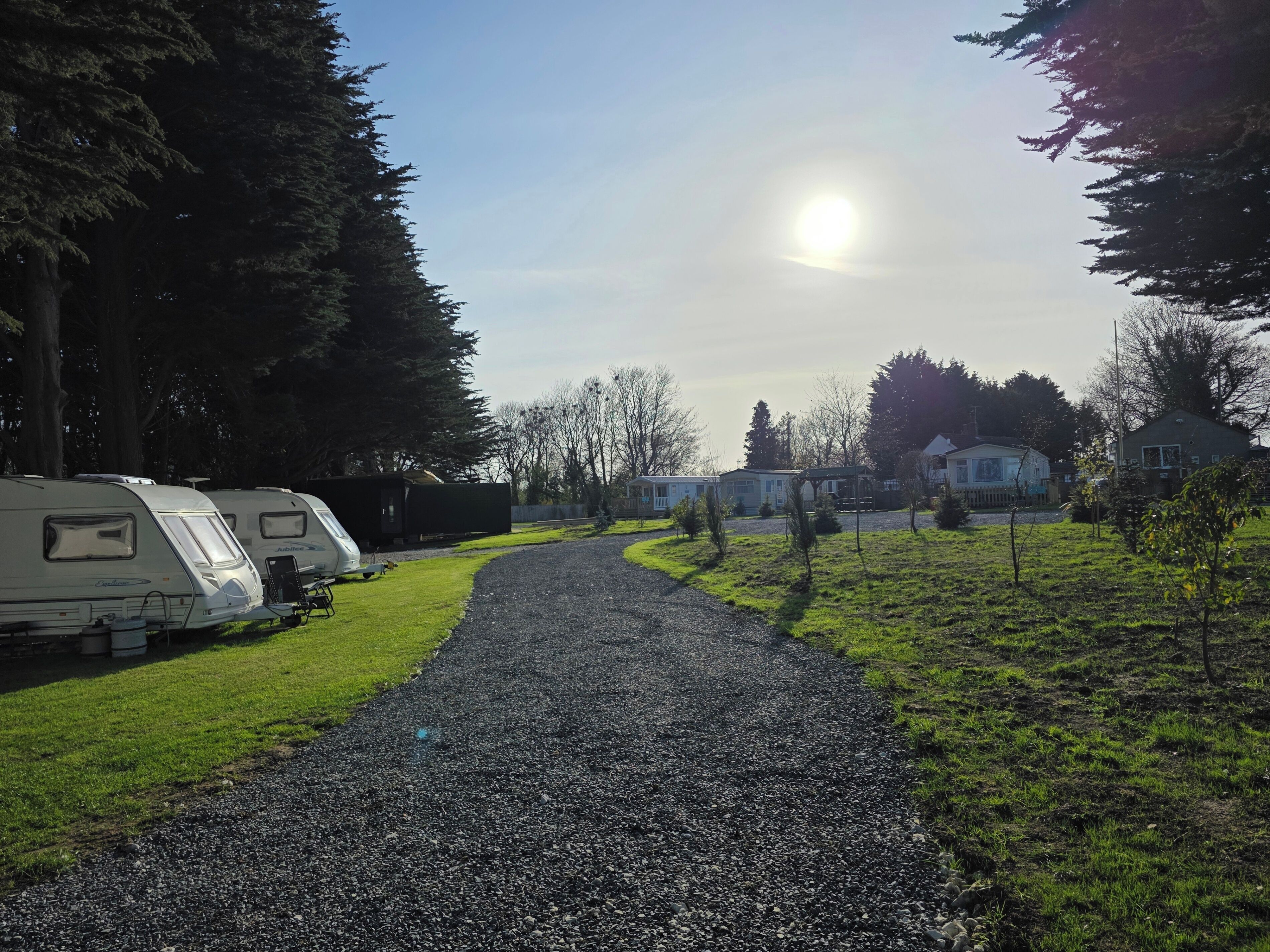 Een grindpad dat leidt naar campers en huizen in een park.
