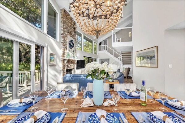 Un coin repas avec une table en bois dressée pour le repas, un vase rempli de fleurs et un escalier menant à l’étage supérieur.