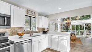 A modern kitchen with white cabinetry, a built-in microwave, and a large island. - Gorgeous Coastal Beach Home w/ Pool, Hilton Head (Hilton Head Island)
