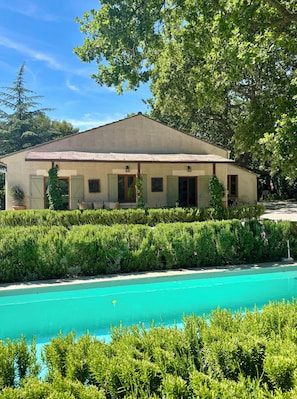 Un bâtiment doté d’une piscine, entouré de verdure et d’arbres.