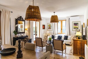 A well-lit living room with a dining area, featuring a sofa set, a coffee table, and a dining table with chairs.