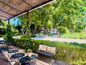 Un espace patio avec des sièges d’extérieur, une pergola et un jardin agrémenté d’un bassin.