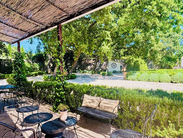 Un espace patio avec des sièges d’extérieur, une pergola et un jardin agrémenté d’un bassin.