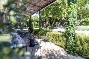 An outdoor patio with a grill, seating, and a pergola.