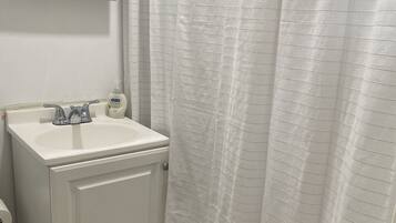 Bañera con ducha, toallas, jabón, papel higiénico