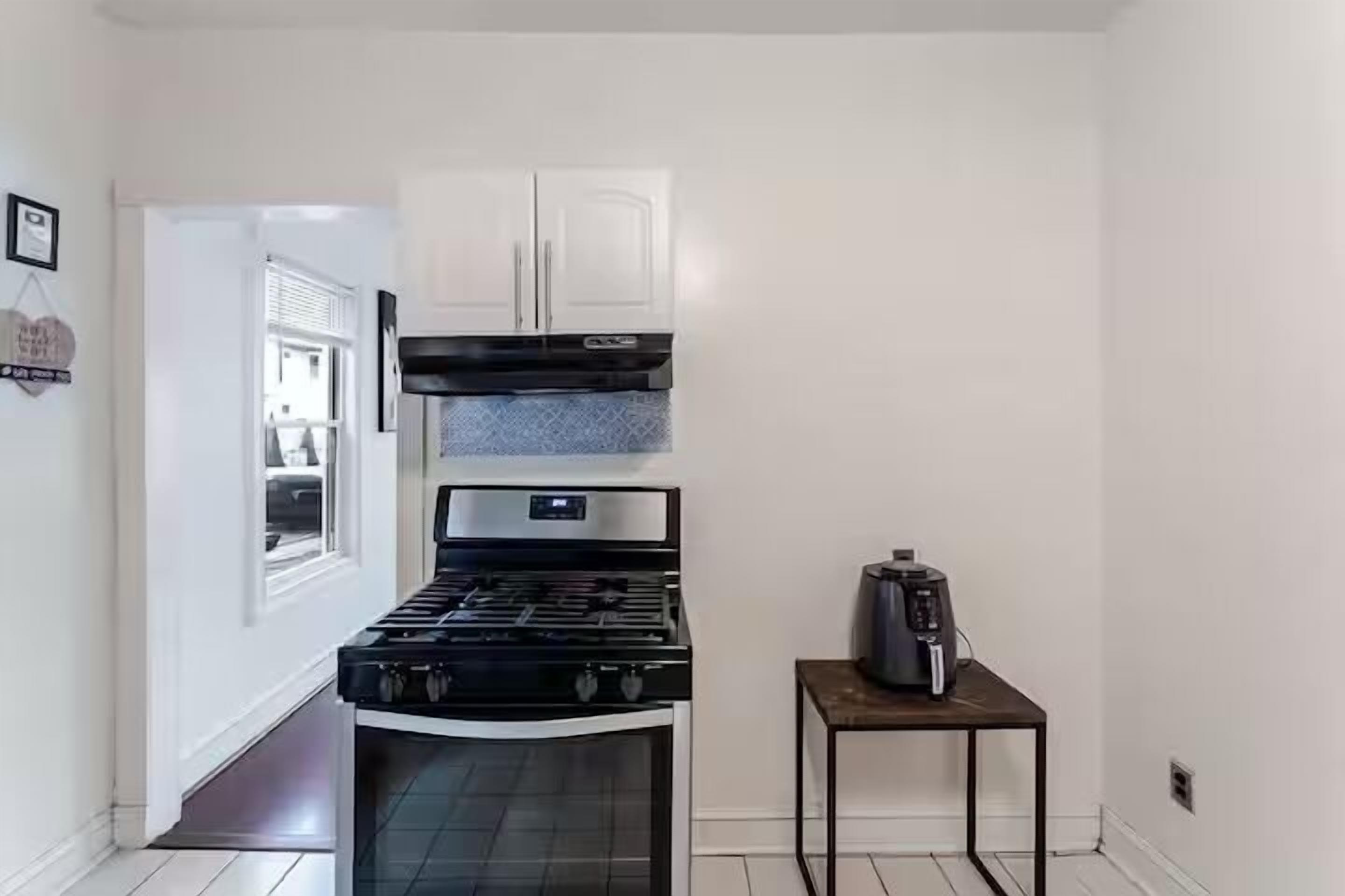 Une cuisine équipée d’une cuisinière, de placards et d’une machine à café posée sur une petite table.