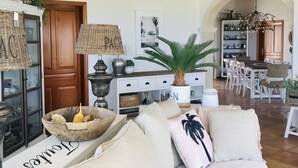 A spacious living room with a large sofa, a dining area with white chairs, and a kitchen in the background. - 400 m2 dream villa / 180 degree panoramic sea view, in top location!  (Dénia)