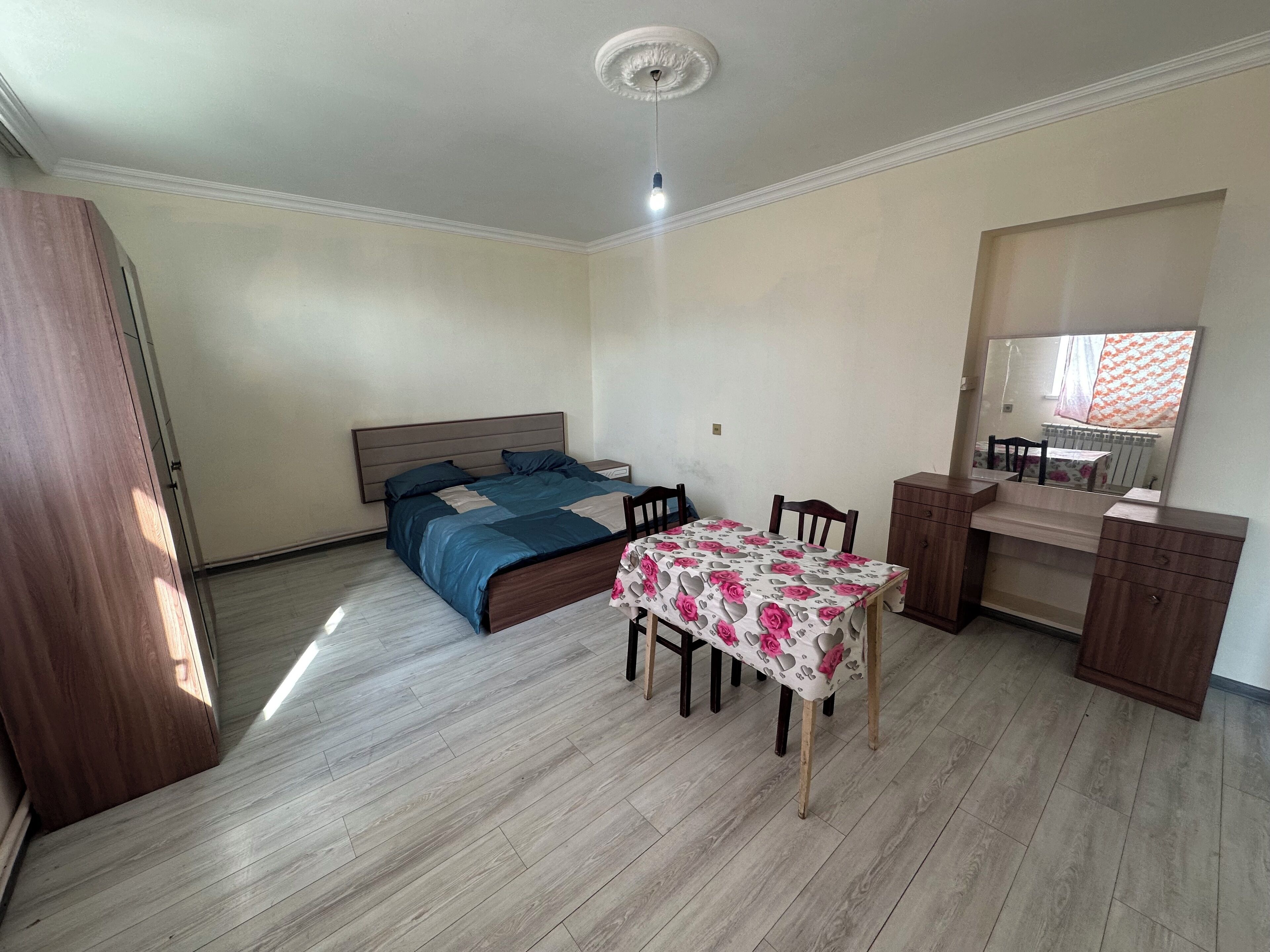 Ein Schlafzimmer mit Bett, Nachttisch, Schminktisch und kleinem Schreibtisch mit Stuhl.