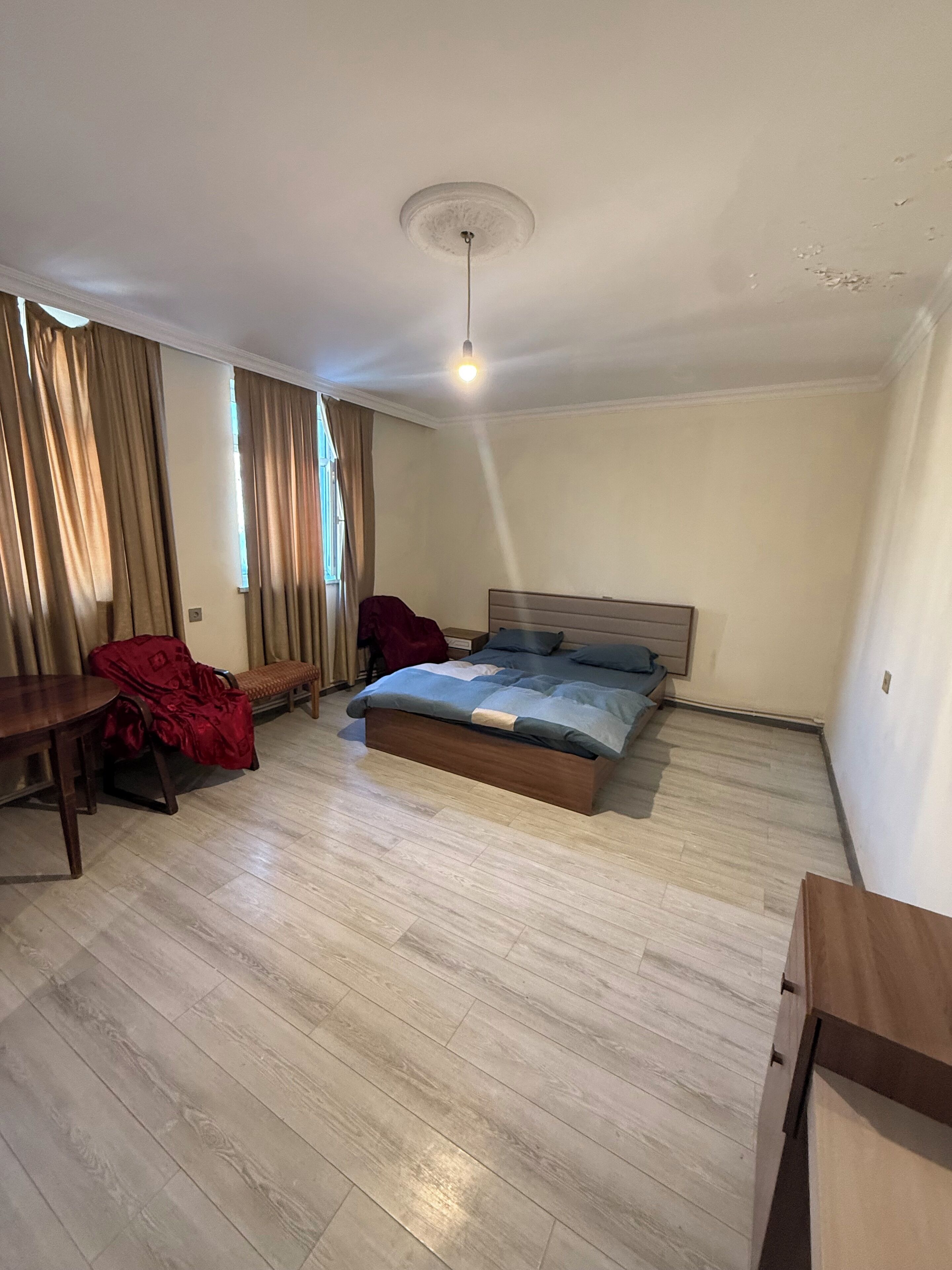 A bedroom with a bed, a wooden desk, a chair, and a bench.