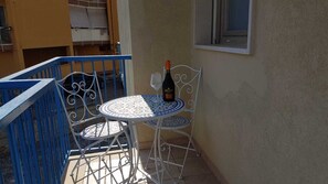 A small outdoor seating area with a round table and two chairs, a bottle of wine, and a window. - Casa Vittoria, a charming vacation home just 5 minutes from the beach. (Monopoli)