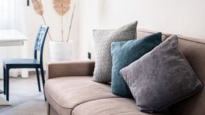 Een beige bank met drie kussens in een woonkamer.