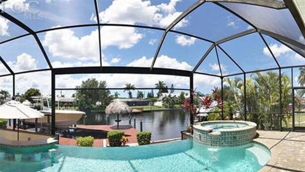 Piscina coberta com hidromassagem, rodeada por palmeiras e vista para um lago.
