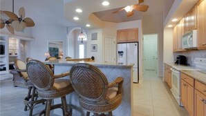 Uma cozinha ampla com ilha central, armários de madeira e ventilador de teto.