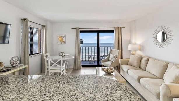 Una habitación de hotel moderna con balcón, zona de comedor y sala de estar.