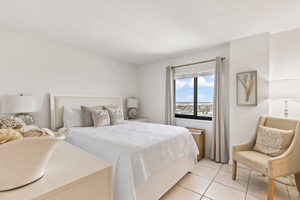 Une chambre d’hôtel avec un lit, une chaise, un bureau et une fenêtre donnant sur un paysage agréable.