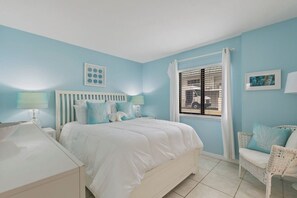 A bedroom with a bed, nightstands, a chair, and a window with blinds.