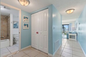 A bathroom with a shower, toilet, and a white door with a red sign. - Poolside Suite 101 | Beach Front, Pool & Hot Tub (Daytona Beach Shores)