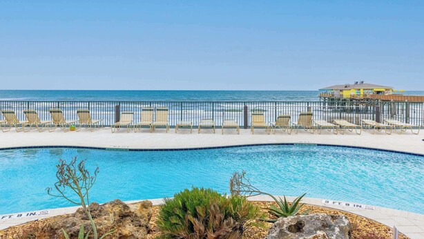 A pool area with lounge chairs and a view of the ocean. - Poolside Suite 101 | Beach Front, Pool & Hot Tub (Daytona Beach Shores)