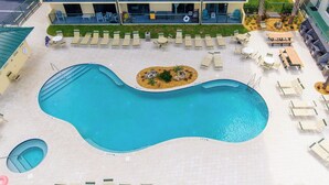 Ein großer, unregelmäßig geformter Pool mit Liegestühlen und Tischen darum herum, und ein kleiner, kreisförmiger Pool in der Nähe.