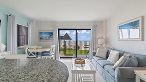 Ein modernes Wohnzimmer mit Esstisch, einer Couch und Blick auf einen Balkon mit Pool.