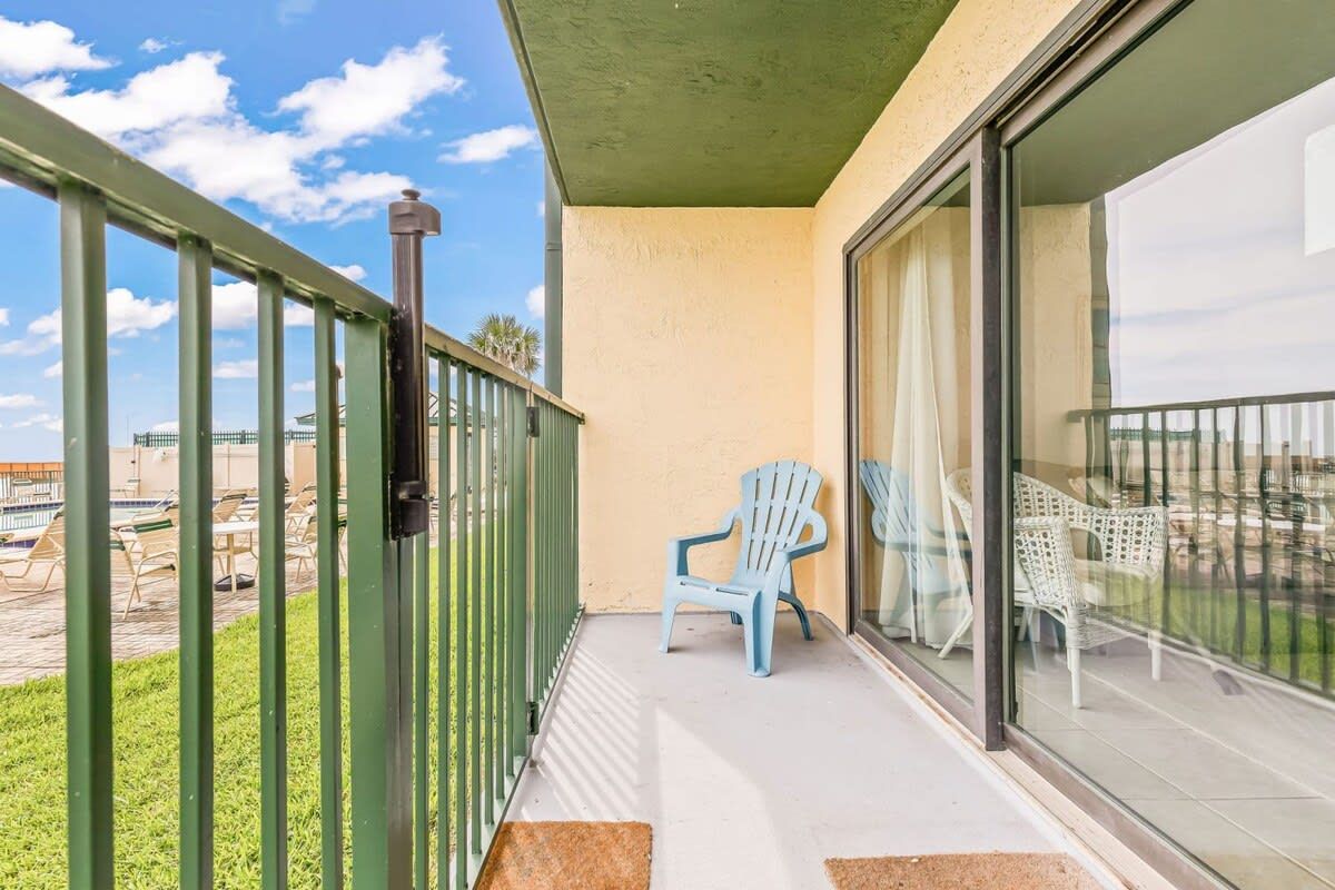 Un balcon doté d’une rambarde en métal, de deux chaises et offrant une vue sur l’espace piscine.