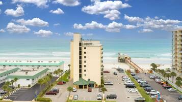Ein Hotel mit Parkplatz, Blick auf den Strand und blauem Himmel.