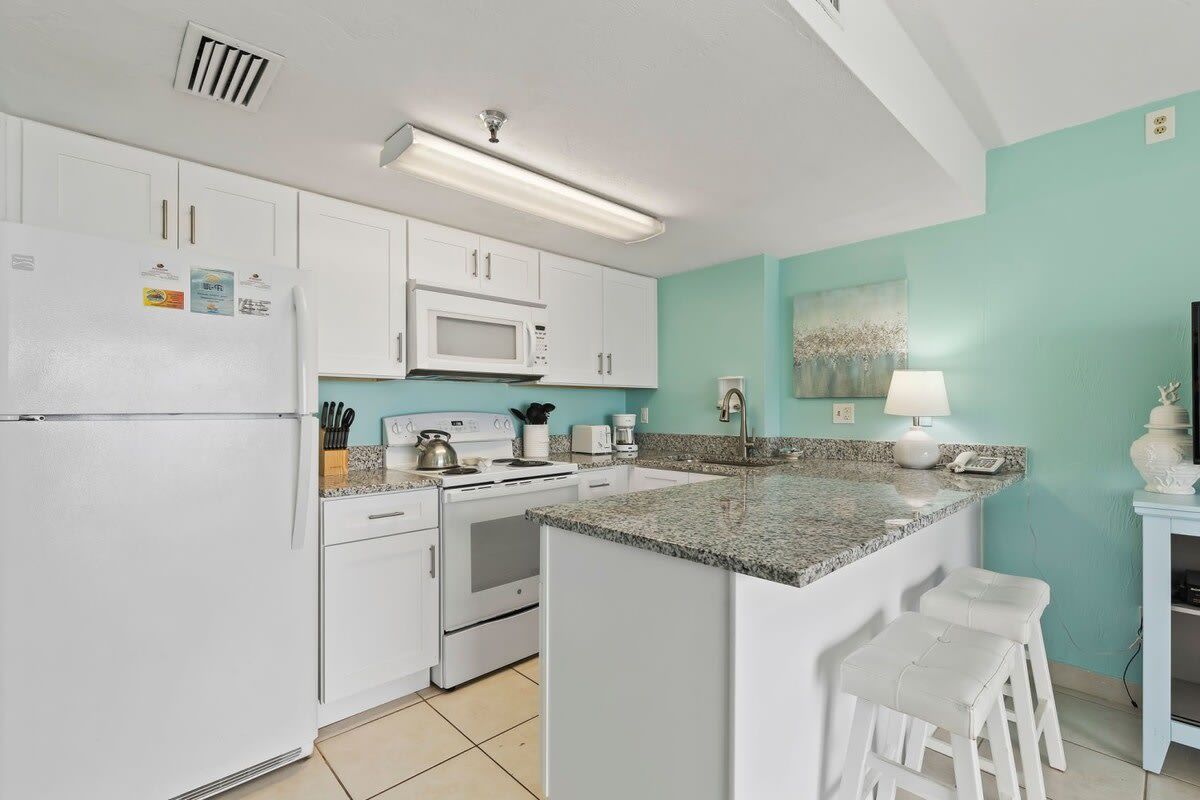 A kitchen with white cabinets, a microwave, a stove, and a granite countertop.