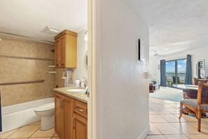 A bathroom with a bathtub, toilet, and wooden cabinets.